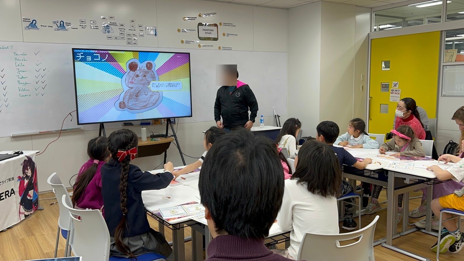 教室前方で講師が AI キャラクター「チョコノ」の解説を行い、子どもたちが机で聞き入る様子
